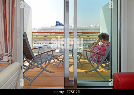 Celebrity Cruises Kreuzfahrt Liner ein Passagier lesen Ihr Kindle Sitzen im Freien auf Kabine Kabine Balkon warten Abfahrt von Venedig Europa Stockfoto