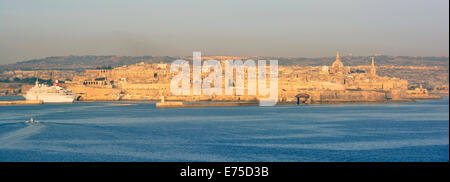 Golden am frühen Morgen Sonnenlicht während Mittelmeer Kreuzfahrtschiff Ansatz nach Valletta mit Sonnenschein am Ufer Gebäude des Grand Harbour Malta Stockfoto