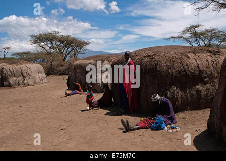 Maasai Frauen inmitten der traditionellen Hütten aus Zweigen mit frischen Kuh eingefügt - Kot und Schlamm, backt Hart unter der heißen Sonne in der Ngorongoro Conservation Area im Krater im Hochland von Tansania Ostafrika Stockfoto