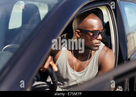Bild von gut aussehenden jungen Mann in seinem Auto sitzen. Männliches Modell mit Sonnenbrille im Auto. Afro-Amerikaner. Stockfoto