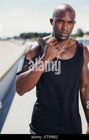 Porträt von Fit junger Mann im freien Musik über Kopfhörer hören. Gesunde, muskulöser Mann mit Arm-Band. Stockfoto