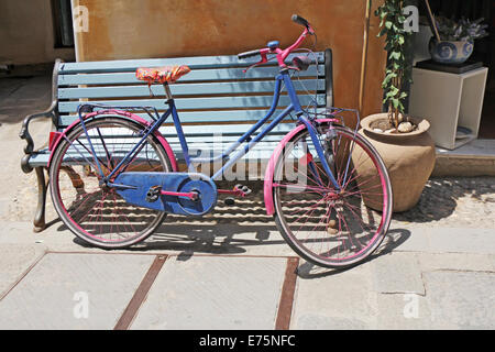 Alte rostige Oldtimer Fahrrad gelehnt blaue Holzbank Stockfoto