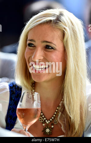 Junge Frau trägt eine Dirndl Kleid hält eine Glas Weine, lächelnd, Stuttgart, Baden-Württemberg, Deutschland Stockfoto