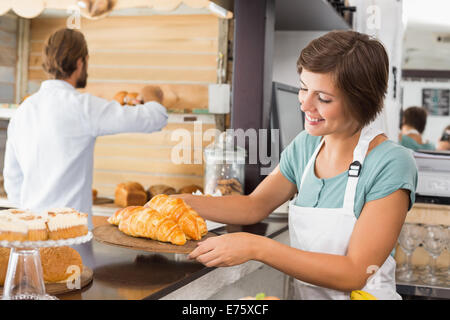 Hübsche Kellnerin hält Tablett mit croissants Stockfoto
