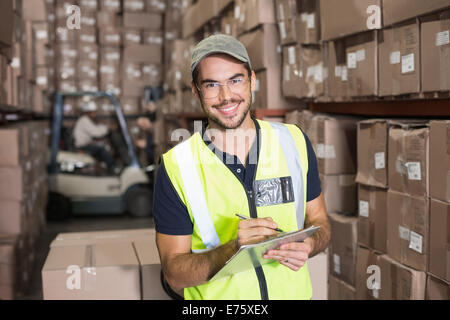 Lagerarbeiter, lächelnd in die Kamera mit Zwischenablage Stockfoto