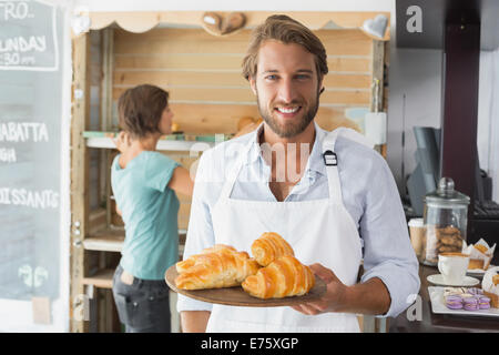 Hübscher Kellner mit Tablett mit croissants Stockfoto