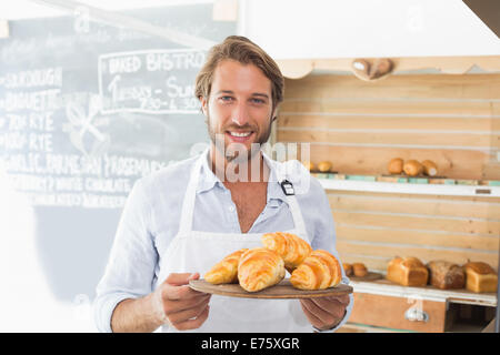 Hübscher Kellner mit Tablett mit croissants Stockfoto