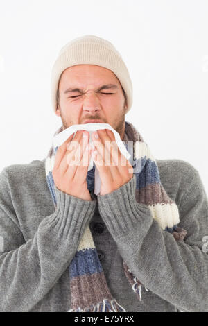 Junger Mann in warme Kleidung Niesen Stockfoto