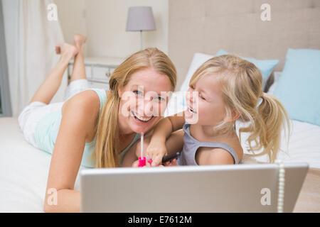 Niedliche kleine Mädchen und Mutter im Bett mit laptop Stockfoto