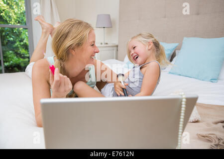 Niedliche kleine Mädchen und Mutter im Bett mit laptop Stockfoto