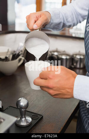 Barista Gießen Milch in Kaffee Stockfoto