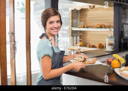 Hübsche Kellnerin hält Teller mit Essen Stockfoto