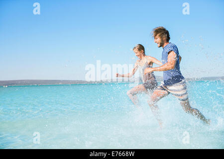 Paar am Strand im Wasser laufen Stockfoto