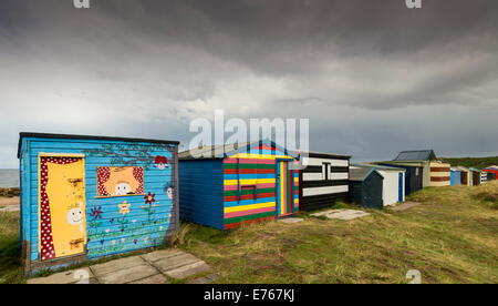 CHALETS AM STRAND HOPEMAN MORAY REGENWOLKEN VORBEI ÜBER EINE REIHE VON BUNTEN HÜTTEN Stockfoto