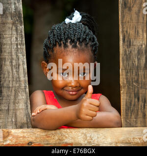 Porträt der kleinen afrikanischen Mädchen tun Daumen oben am Holzzaun. Stockfoto