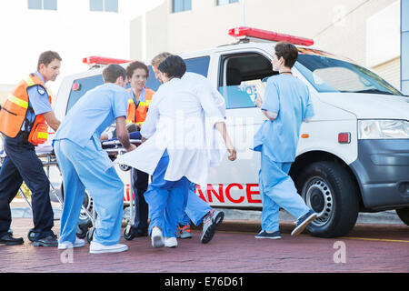 Ärzte, Krankenschwestern und Sanitäter untersuchen Patienten auf Keilrahmen Stockfoto