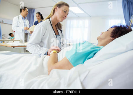 Arzt im Gespräch mit Patienten im Krankenhausbett Stockfoto