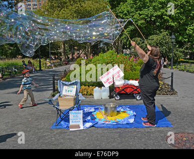 Frau im Washington Square Park in New York City große Seifenblasen und unterhalten Kinder.
