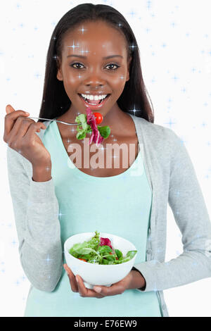 Zusammengesetztes Bild der lächelnde junge Frau essen Salat Stockfoto