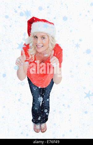 Zusammengesetztes Bild blonder Frau ihre Daumen aufstellen, während des Tragens Weihnachten Kleidung Stockfoto