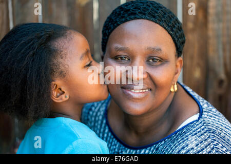 Porträt von kleinen Mädchen küssen Mutter auf Wange im freien hautnah. Stockfoto