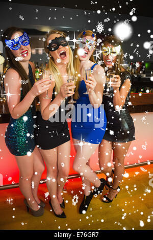 Zusammengesetztes Bild des Lachens Freunde mit Masken auf hält Champagner Stockfoto