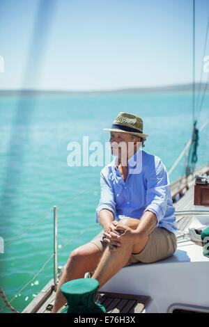 Älterer Mann sitzt auf Boot im freien Stockfoto