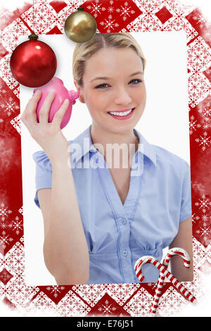 Zusammengesetztes Bild des lächelnden Frau schütteln ihr Sparschwein Stockfoto