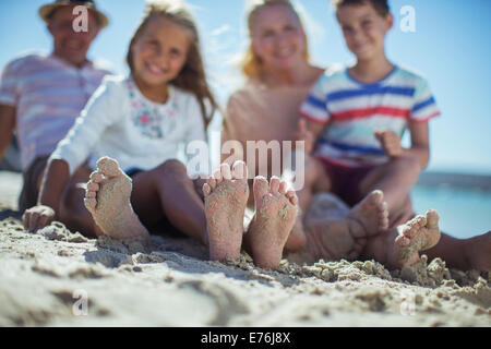 Familie sitzt zusammen mit Füße im sand