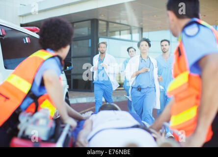 Ärzte und Krankenschwestern hetzen, um Patienten auf Krankenwagen Bahre Stockfoto