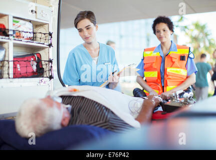 Rettungssanitäter und Krankenschwester untersuchen Patienten in Ambulanz Stockfoto