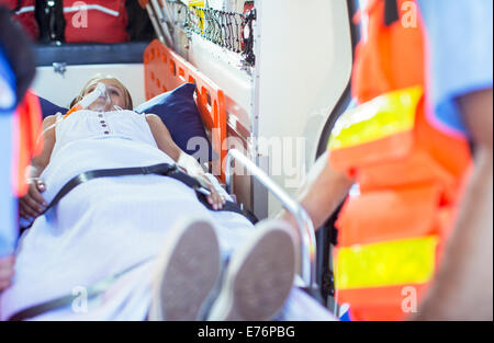 Rettungssanitäter Prüfung Patienten auf Bahre in Ambulanz Stockfoto