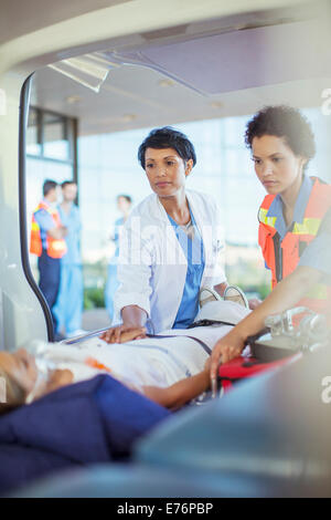 Arzt und Sanitäter untersuchen Patienten in Ambulanz Stockfoto