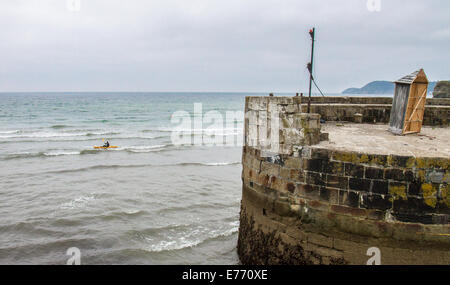 Ein Kanufahrer paddeln aus dem Hafen von Charlestown, ein Dorf und Hafen an der südlichen Küste von Cornwall, England UK Stockfoto