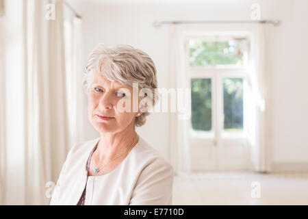 Ältere Frau im leeren Wohnzimmer Stockfoto