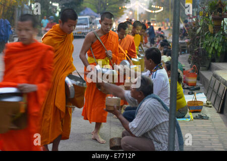 Luang Prabang, Laos - 2. März 2014: Mönche gehen um Almosen und Angebote in Luang Prabang, Laos zu sammeln. Stockfoto