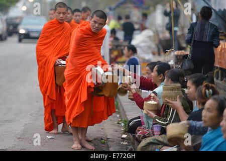 Luang Prabang, Laos - 2. März 2014: Mönche gehen um Almosen und Angebote in Luang Prabang, Laos zu sammeln. Stockfoto