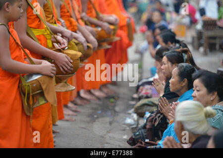 Luang Prabang, Laos - 2. März 2014: Mönche gehen um Almosen und Angebote in Luang Prabang, Laos zu sammeln. Stockfoto