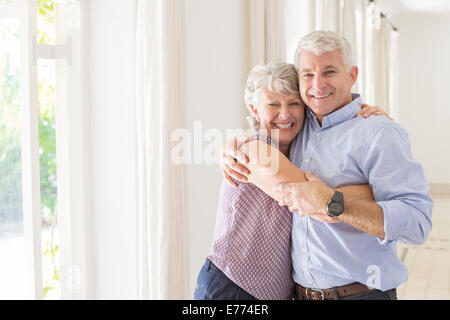 Älteres Ehepaar umarmt im Wohnraum Stockfoto