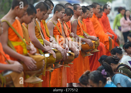 Luang Prabang, Laos - 2. März 2014: Mönche gehen um Almosen und Angebote in Luang Prabang, Laos zu sammeln. Stockfoto