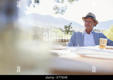 Älterer Mann sitzt am Esstisch im freien Stockfoto