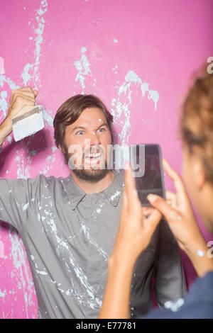 Frau unter Bild mit Handy-der Mann mit Pinsel Stockfoto