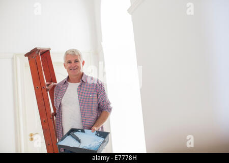 Älterer Mann mit Leiter und Farbe Tablett Stockfoto