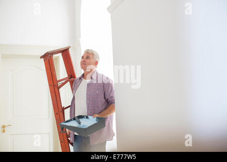 Älterer Mann mit Leiter und Farbe Tablett Stockfoto