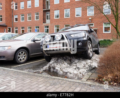 SUV 4x4 Auto in einer üblichen Weise geparkt auf einem großen Haufen Schnee. Sahlgrenska Krankenhaus, Västra Götaland, Schweden. Model Release: Nein Property Release: Nein. Stockfoto