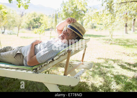 Älterer Mann entspannend auf Rasen Stuhl im freien Stockfoto