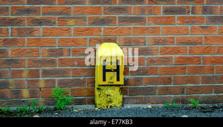 Ein gelber Hydranten Zeichen gegen eine gemauerte Wand England uk Stockfoto