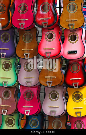 Mehrere Gitarren in verschiedenen Farben, die in Reihen an der Wand hängen. Stockfoto