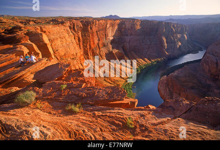 Besucher über Horseshoe Bend am Colorado River in der Nähe von Glen Canyon Dam und Page, Arizona bei Sonnenuntergang Stockfoto