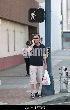 Piers Morgan 3/4 Länge tragen shorts wartet, überqueren Sie die Straße mit seinem Imbiss in einer Plastiktüte, während der Einnahme eines Anrufs auf seinem Handy mit Telefon: Piers Morgan Where: Los Angeles, California, Vereinigte Staaten von Amerika bei: 6. März 2014 Stockfoto